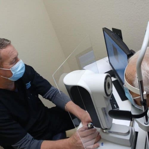 Dr. Collins performs an eye exam on an elderly patient with cataracts