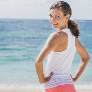 A woman at the beach looks back smiling